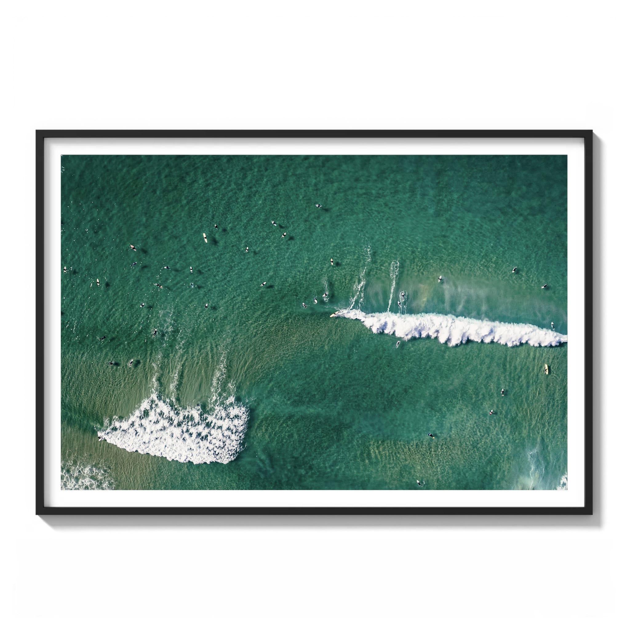 Aerial color photograph of surfers scattered across teal water with branching whitewater patterns at the Northern Beaches, Sydney framed.