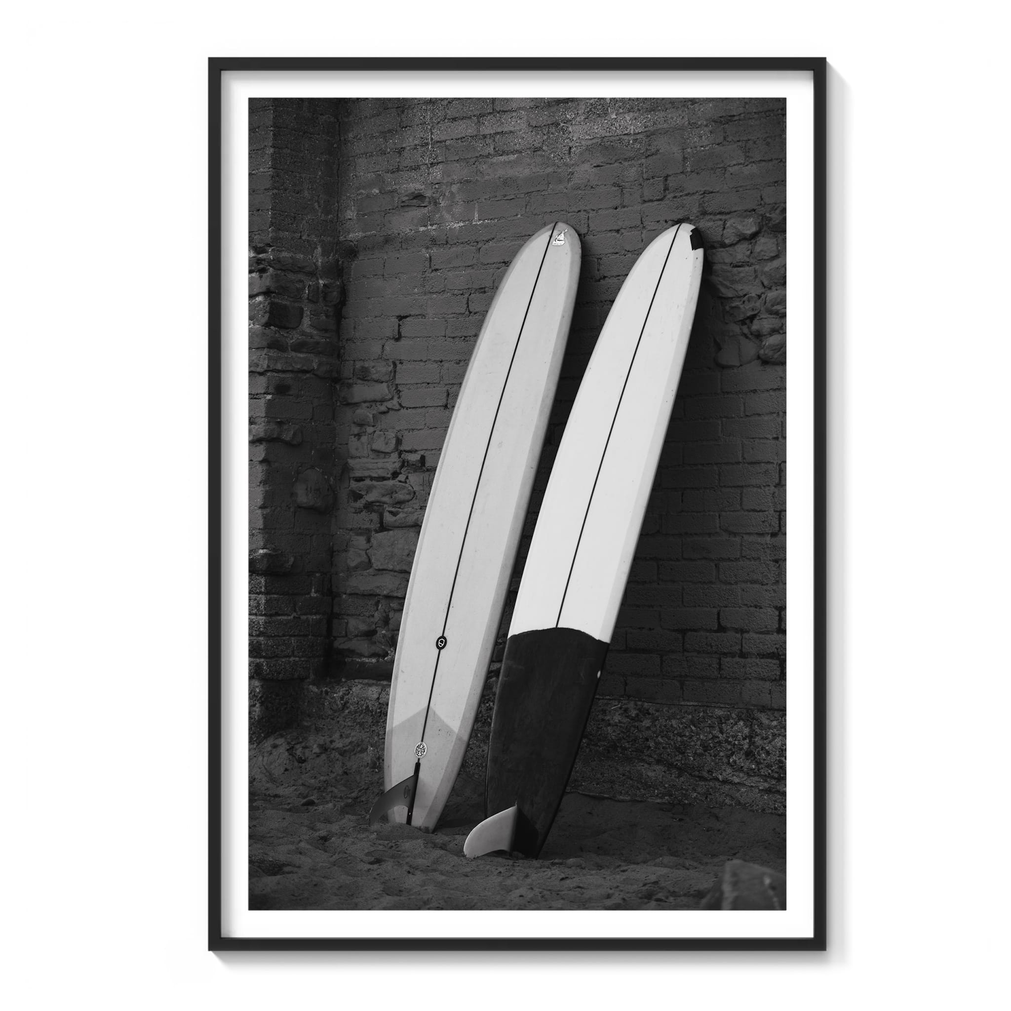 Framed black and white photograph of two longboards leaning against a brick wall in Malibu.