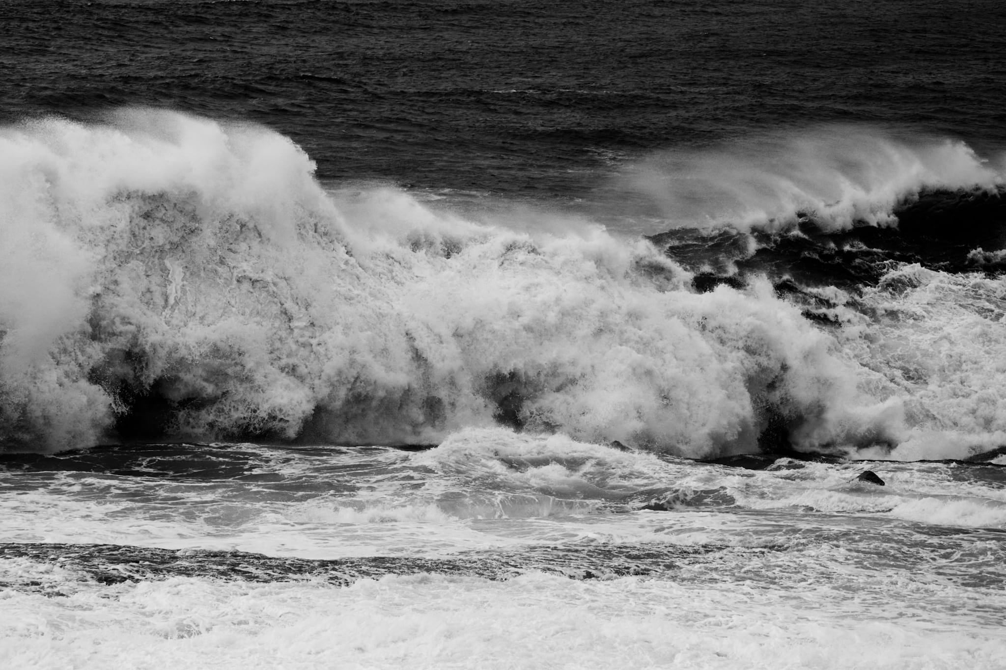 Black and white photograph of a large wave collapsing into whitewater along the NSW mid-coast.