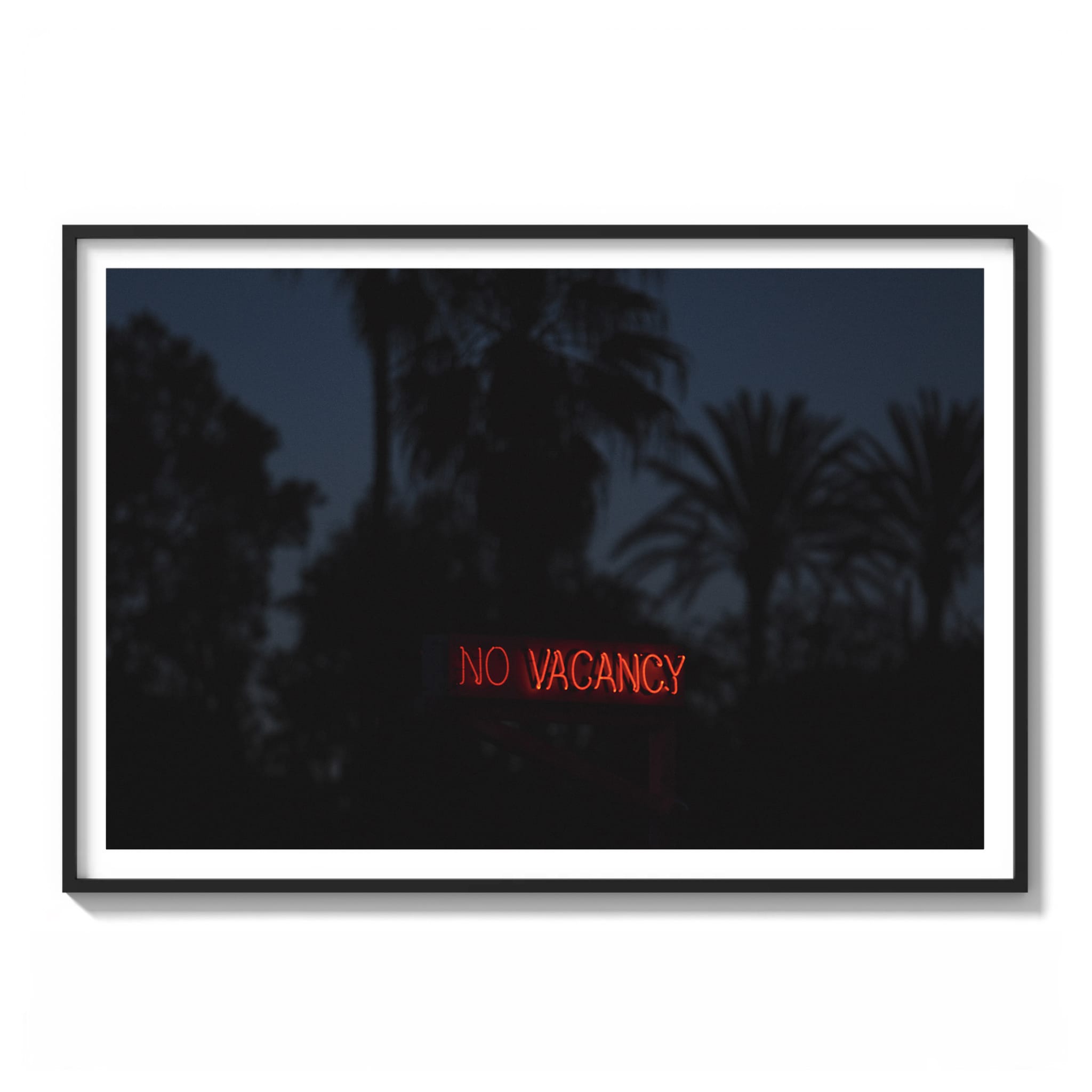 Framed color photograph of a glowing red "No Vacancy" neon sign against a dark blue dusk sky with palm tree silhouettes in Los Angeles.