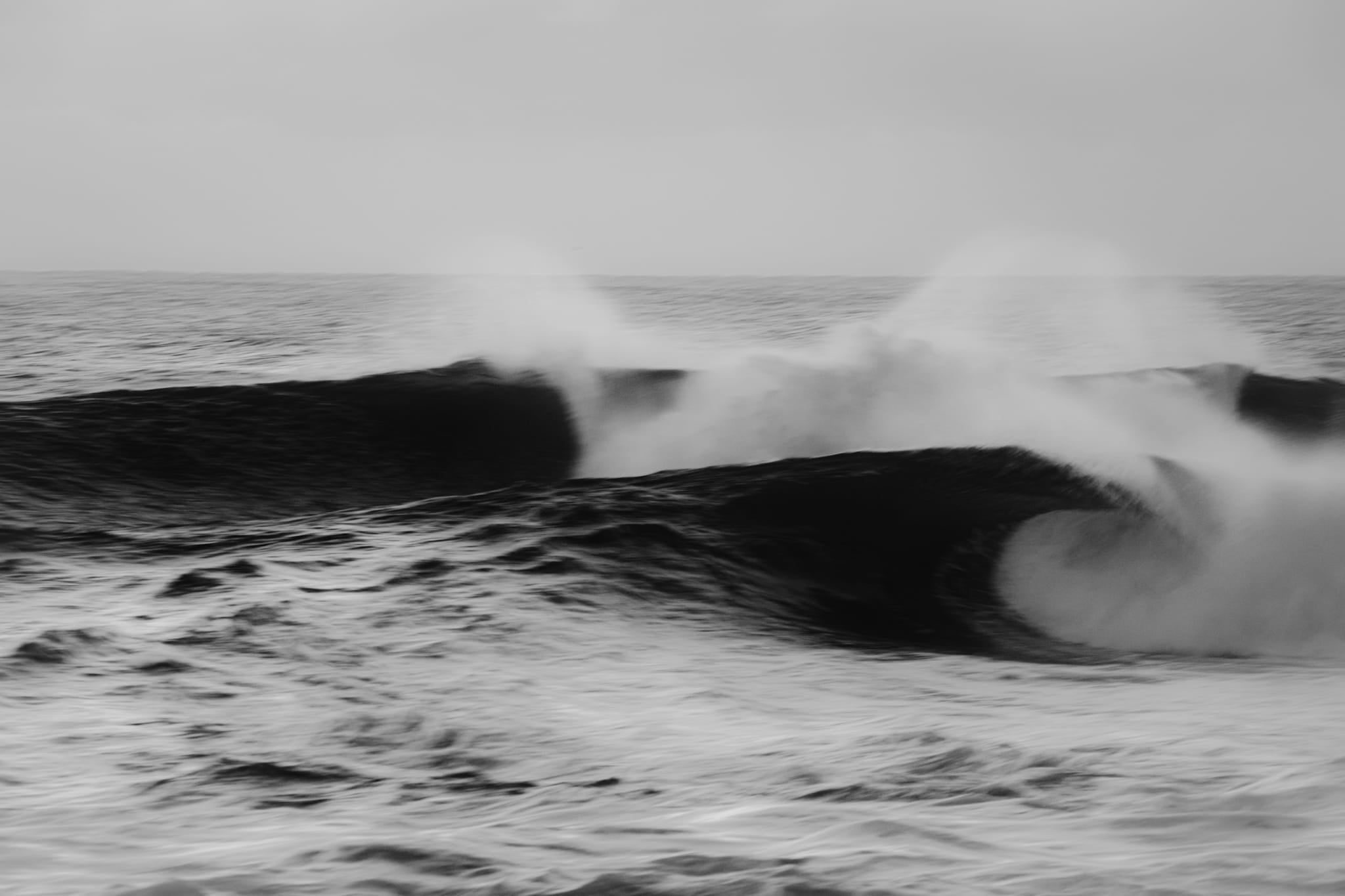 Black and white long-exposure photograph of two wave faces off the Sydney coast with soft, misty spray.