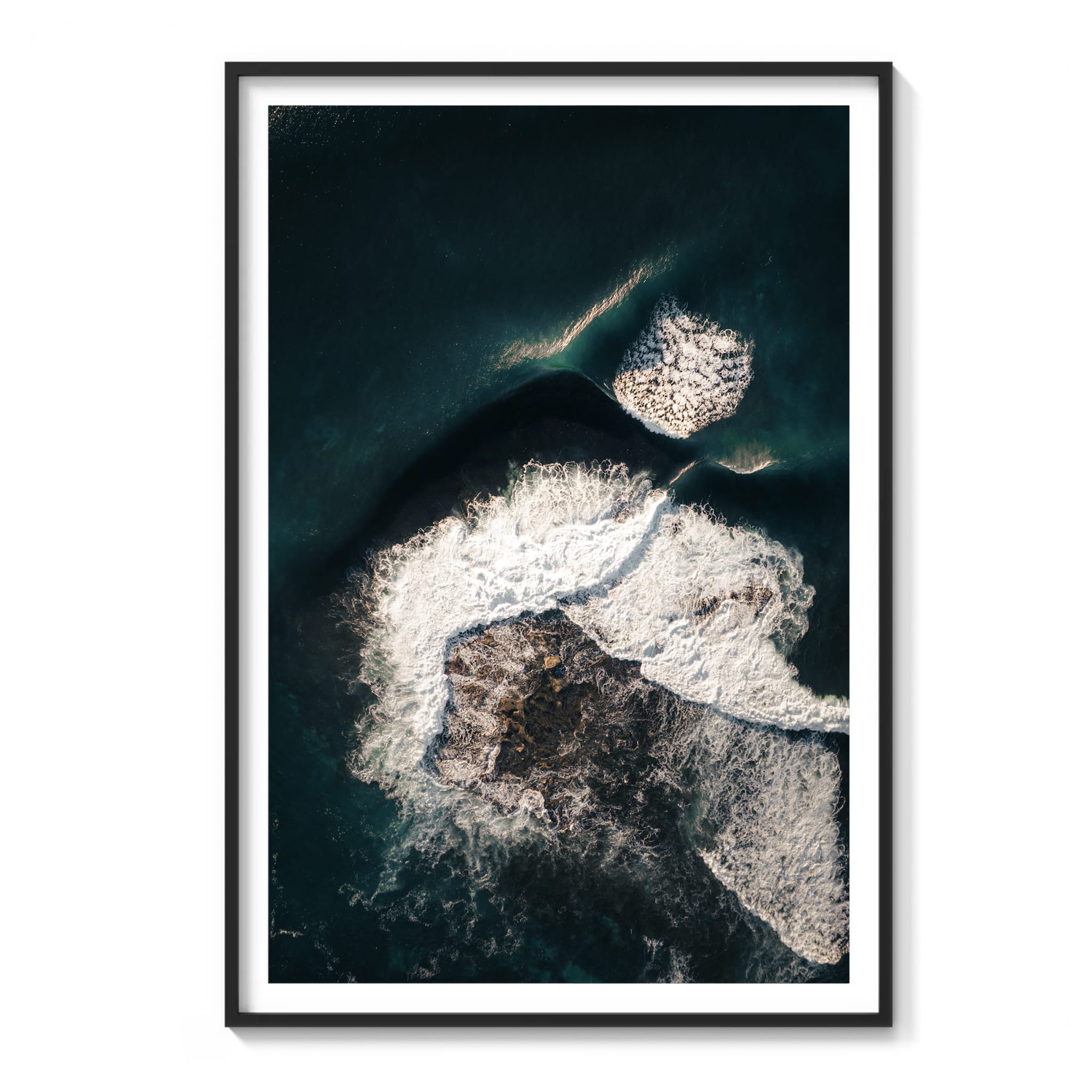 Framed aerial color photograph of dark rock and turquoise water with foam patterns at Shark Island, Sydney.