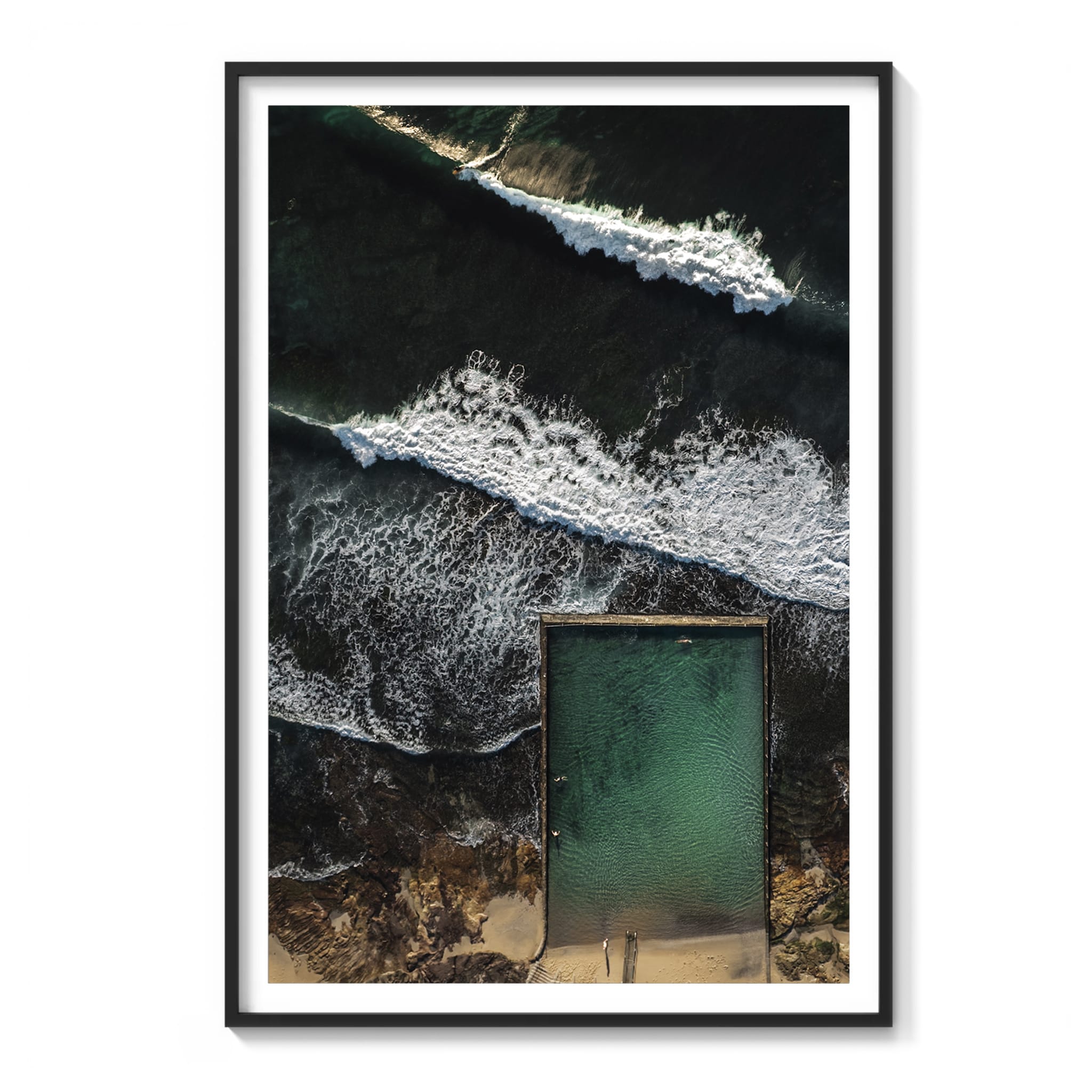 Framed aerial color photograph of a rectangular ocean rock pool beside crashing waves at Cronulla at sunrise.