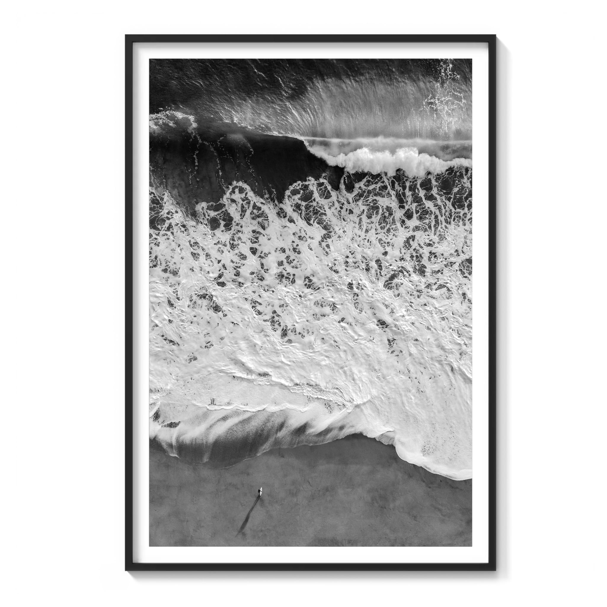  Framed aerial black and white photograph of a lone figure standing on the beach beside lace-like patterns of retreating whitewater, Southern California.