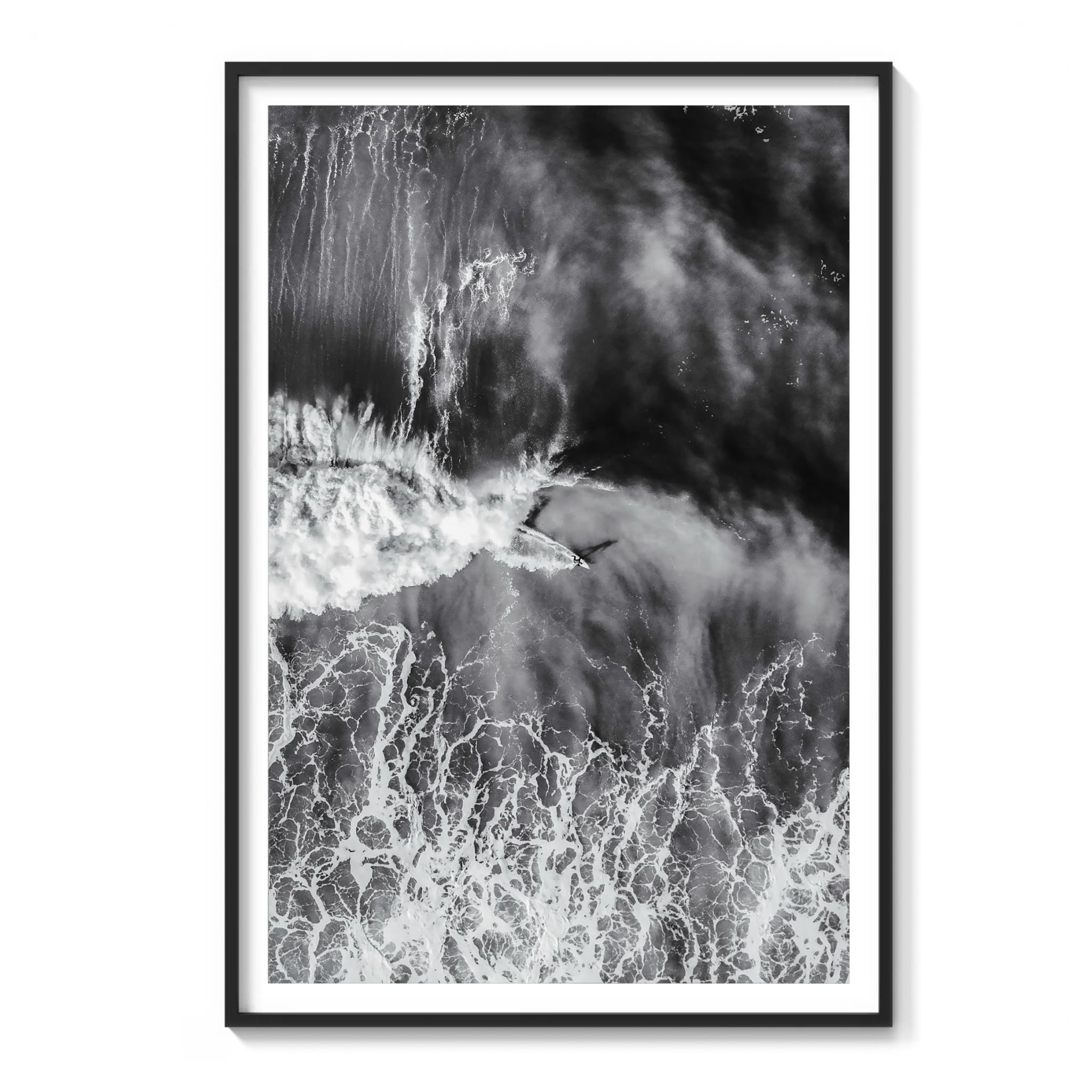 Framed aerial black and white photograph of a surfer riding a textured wave face at Ocean Beach, San Francisco.
