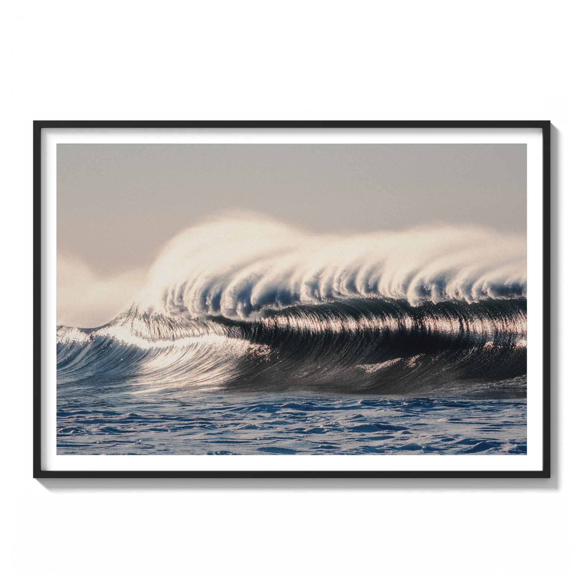 Warm sunrise photograph of a glassy, wind-groomed wave along the Malibu coastline with soft golden light framed.