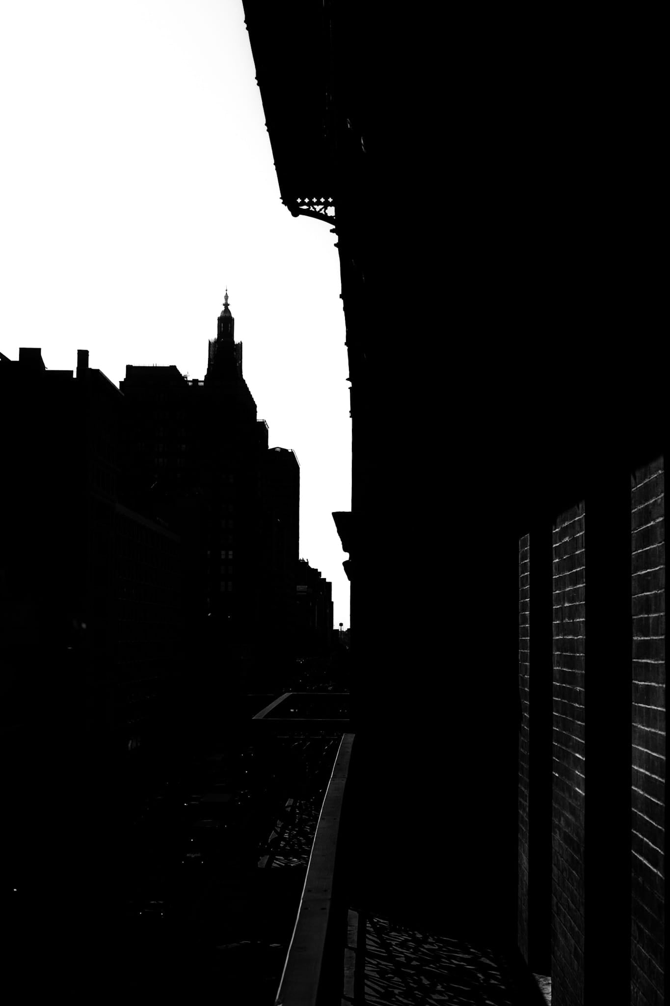 Black and white photograph of a building silhouette and fire escape against the Manhattan skyline near the Chelsea Hotel, New York City.
