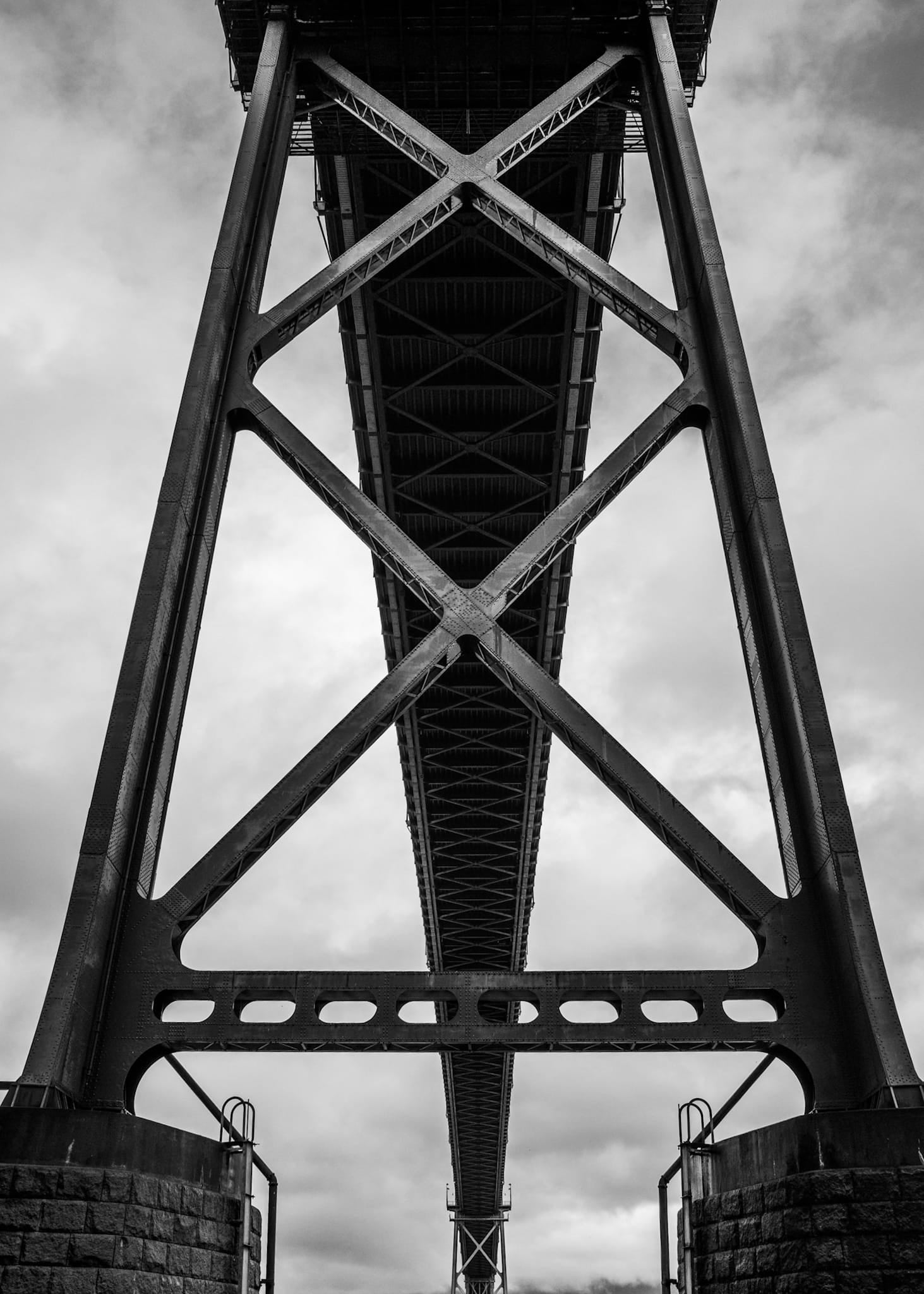 Black and white photograph of a symmetrical steel bridge truss structure viewed from directly below in Vancouver.