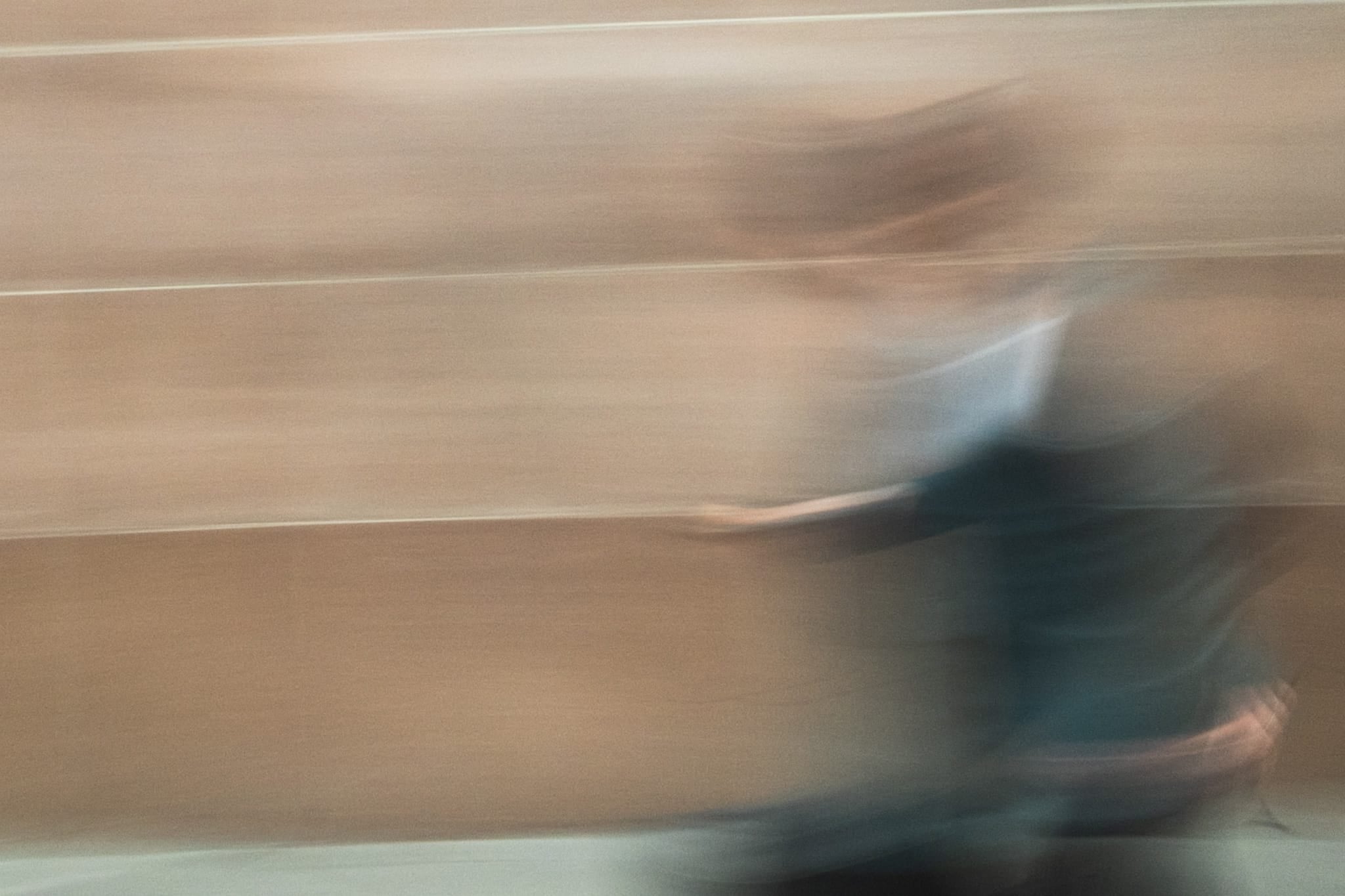 Abstract color photograph of a blurred figure in motion against a warm-toned wall in the Sydney CBD.